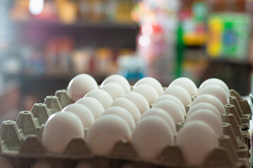 view of several white hen eggs, placed in a glass display case. sale of eggs in a grocery store....