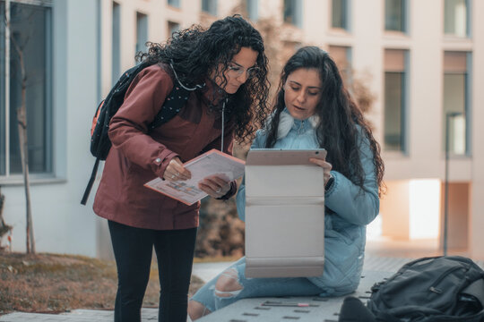 Jovenes chicas adolescentes revisando sus tareas y apuntes mientras hablan sobre los temas del instituto junto con su tablet y documentos de la escuela
