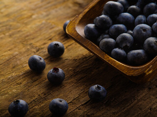 On a wooden table blueberries in a bowl and on the table. Tasty healthy product, vitamins, antioxidants, diet food, healthy lifestyle. Color image. There are no people in the photo.