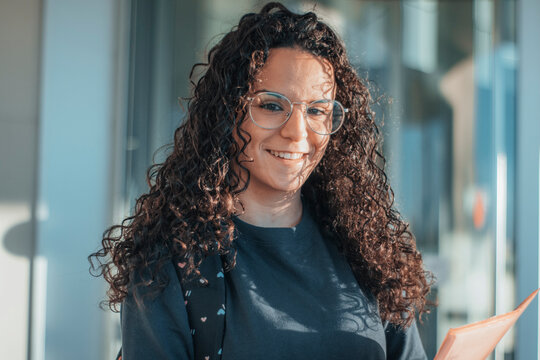 Alumna sonriente con gafas de un instituto de secundaria contenta por acceder a clases junto con sus apuntes de las clases para comenzar su rutina escolar