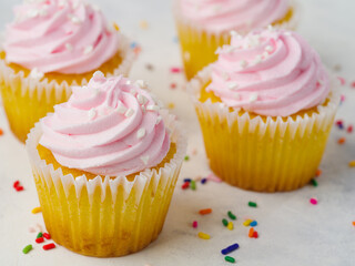 Cake baskets with pink cream on a white background. Colorful confetti scattered around. Holiday, surprise, birthday, congratulations, advertising.