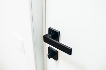 Fototapeta na wymiar Modern white door and black doorknob on interior doors