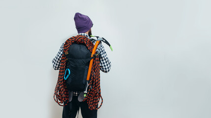 Brutal bearded guy mountaineer with a tourist backpack, an ice ax and a rope is going on a journey. Studio shot