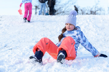 Fototapeta na wymiar Little girl goes downhill on the sledge board