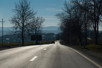 Asphalt road among trees and the village in background. Shamakhi, Azerbaijan.