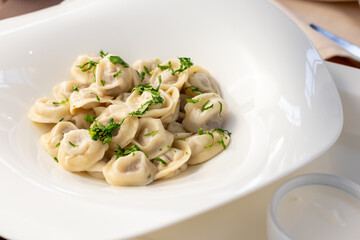 Dumplings with sour cream and herbs on white plate