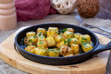 Fried potatoes with mushrooms on black iron pan