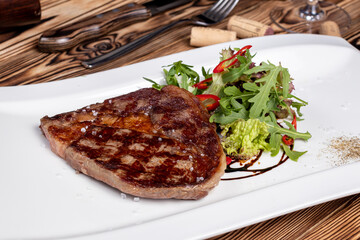 juicy Ribeye steak with vegetables on white plate