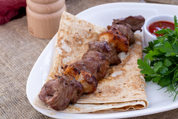 skewers of mutton flesh with sauce and red onion on a white plate
