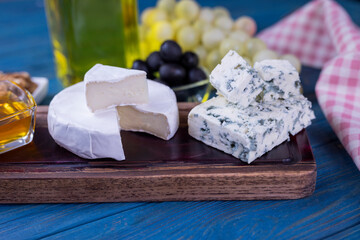 appetizer cheese dor blue and camembert on a wooden board with honey and grapes