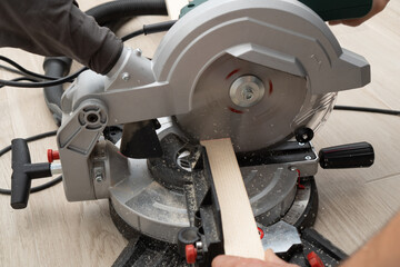 Miter saw in the process of sawing off a wooden part. - obrazy, fototapety, plakaty