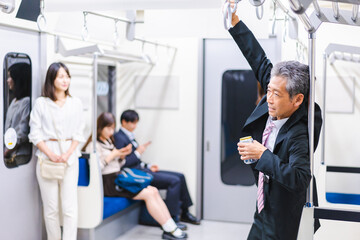 Fototapeta na wymiar 電車内で飲酒をする中年の男性