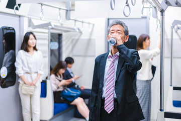 電車内で飲酒をする中年の男性