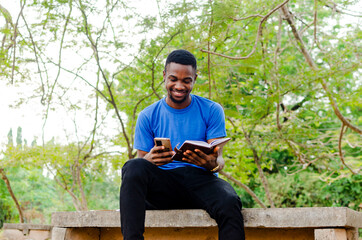 Obraz premium African male school student using campus internet for his assignment