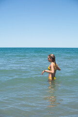 young girl laughing in a turquoise sea. upright photo. space for text. patagonia argentina