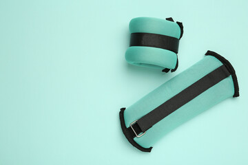 Stylish weighting agents on turquoise background, flat lay. Space for text