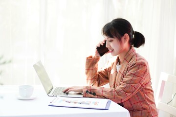 woman talking on phone and working on a laptop