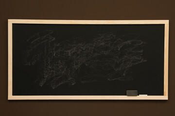 Dirty black chalkboard hanging on brown wall