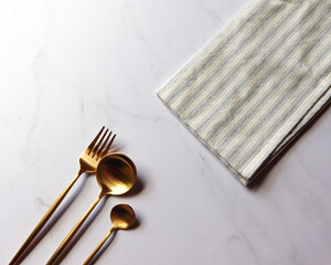 premium gold fork, knife and spoon with marble envelope and white and blue striped napkin