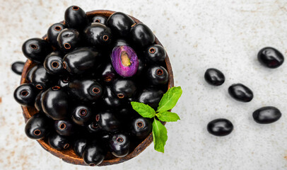 Black ripe Syzygium cumini fruits. Dark black java plum in a wood bowl at isolated white...
