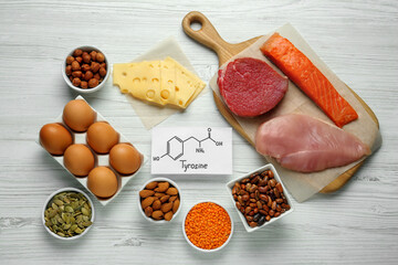 Different fresh products and paper with Tyrosine chemical formula on white wooden table, flat lay. Sources of essential amino acids