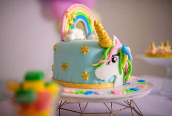 Unicorn-themed birthday cake, pastel colored beautiful cake on the cake stand, birthday party decoration for a 1 year old baby girl. © nilanka