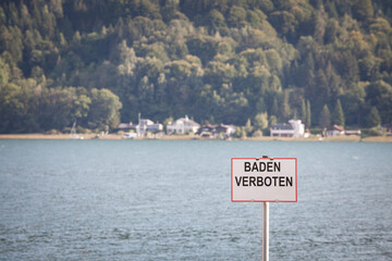 Selective blur on a sign indicating baden verboten, meaning no swimming in german, in the ossiacher...