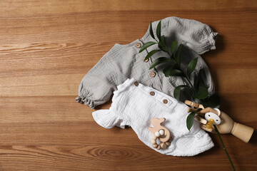 Flat lay composition with children's clothes, toys and pacifier on wooden table. Space for text