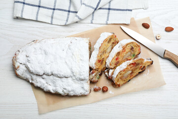 Traditional Christmas Stollen with icing sugar on white wooden table, flat lay