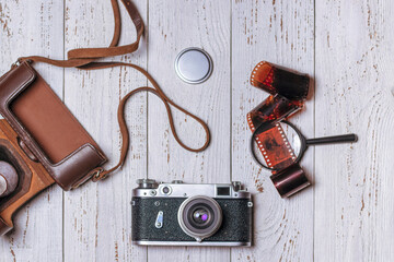 Old retro camera with leather case, magnifying glass and film on white boards