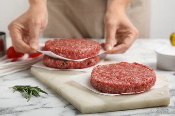 Woman making hamburger patties at white marble table, closeup