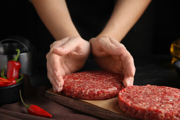 Woman making hamburger patties at wooden table, closeup