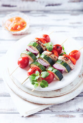 Grilled shashliks with vegetables and pork tenderloin. Bright wooden background. Close up.