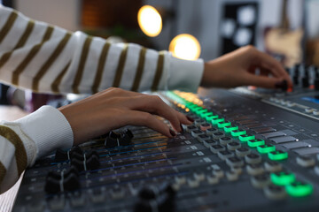 Woman working with professional mixing console in modern radio studio, closeup