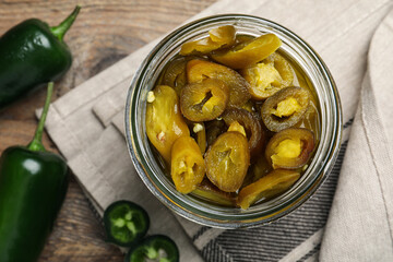 Fresh and pickled green jalapeno peppers on wooden table, flat lay