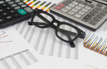 Two calculators and eyeglasses on financial data documents. Business statistics concept.