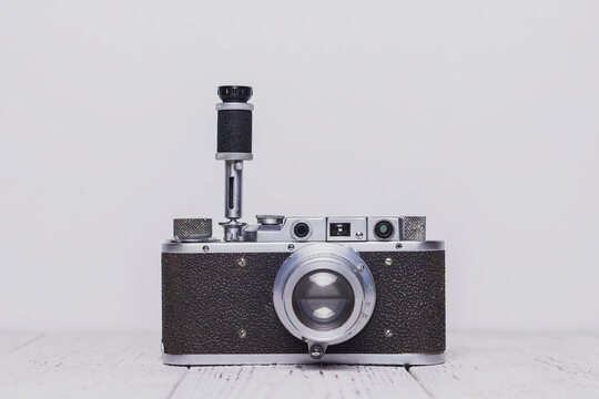 An old retro self-timer camera stands on a wooden table