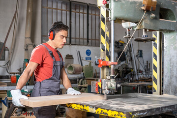 Serious male woodworker cutting wood on band saw