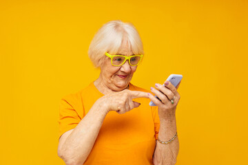 Portrait of an old friendly woman in casual t-shirt communication by phone technologies