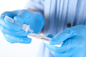 Hand of doctor drops reagent onto coronavirus (Covid 19) antigen test kit, medical concept, and...