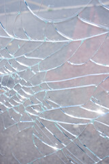 Broken glass with cracks on blue sky background. Close up view of broken glass texture
