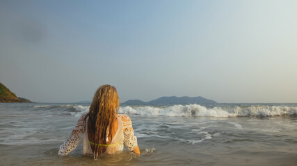 Woman in a White Tunic on the Beach, near the Sea. Blonde in Sun