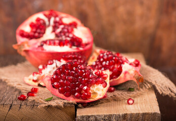 Juicy pomegranate and its half Beautiful composition with juicy pomegranates, on old wooden table