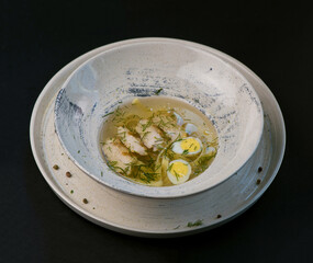 broth with noodles and quail egg in a white plate on a black background