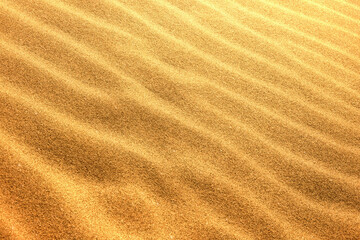 Fototapeta na wymiar 砂紋　砂模様ゴールド金色テクスチャ背景素材　光で輝く美しい砂漠砂丘イメージ写真素材