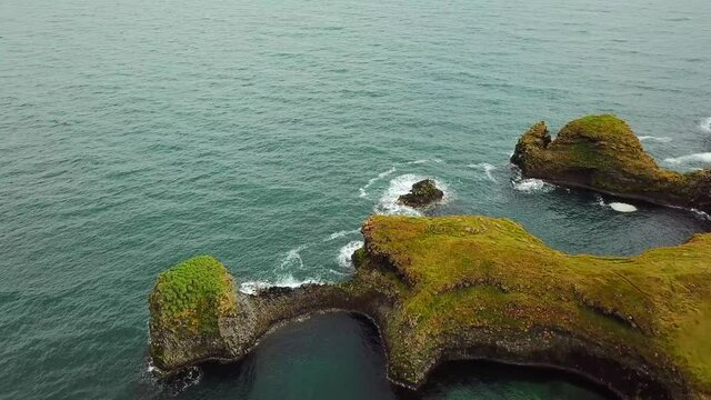 Amazing seascape, Gatklettur basalt rock arch at the volcanic cliff, Atlantic coast of Arnarstapi in the west of Iceland. Rocks and stones with abstract forms. Drone footage. Hollow in the ground. 