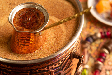 Traditional Turkish coffee with foam in cezve prepared on hot sand in authentic Turkish Copper.
