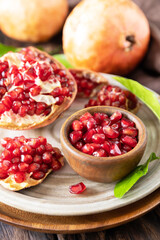 Ripe juicy pomegranate fruits in a wooden bowl on a rustic table closeup. Diet and healthy food.