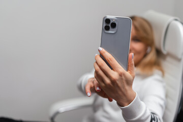 Beautiful young woman taking selfie while sitting on white computer chair at home