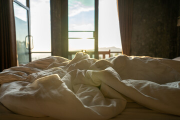 White blankets on the bed, natural light in the bedroom in the morning.